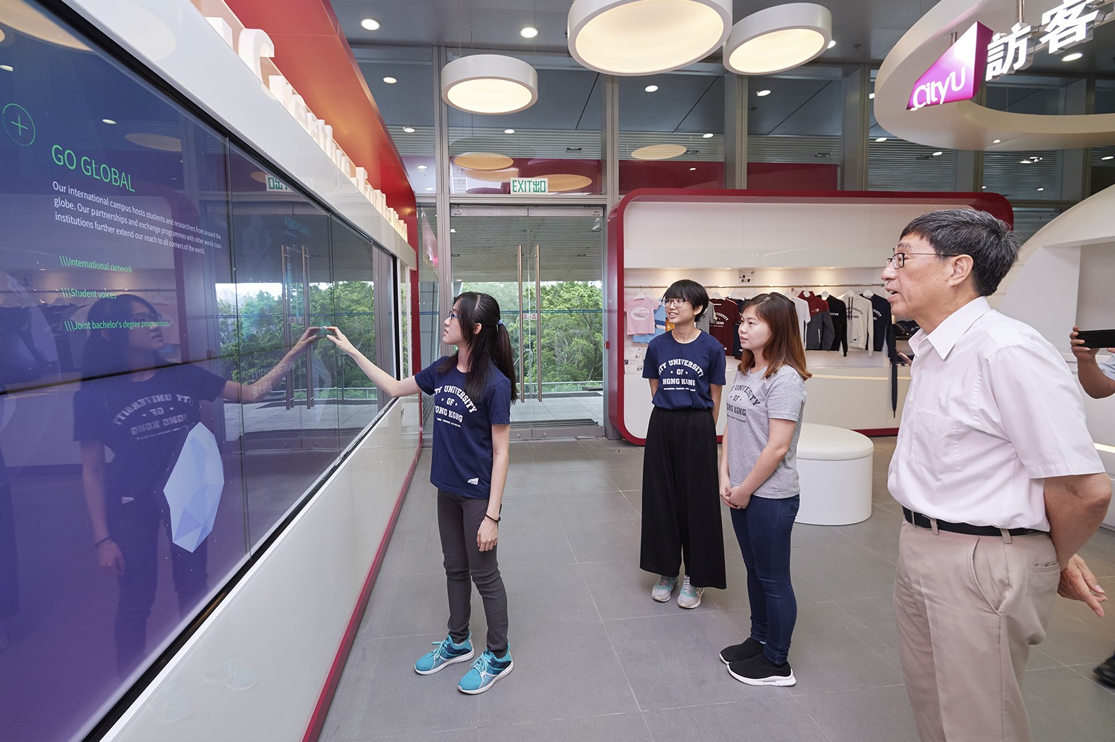 Student helpers show Professor Kuo how the interactive digital panel on the TV Wall works.