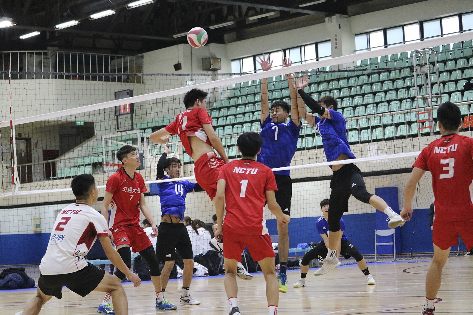 Men’s teams from CityU (blue tops) and NCTU (red tops) compete in volleyball. (Photo credit: NCTU)